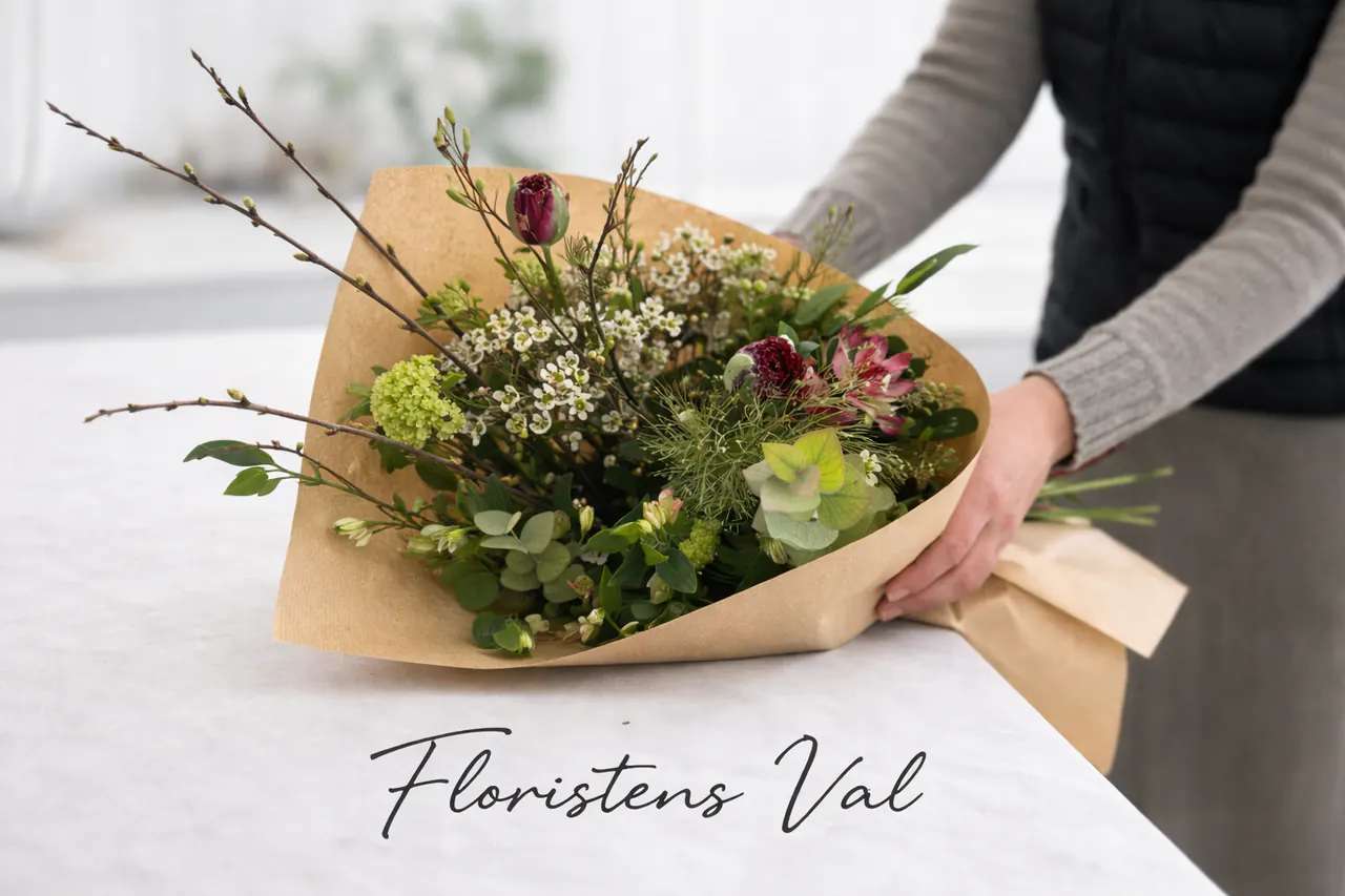 Florist som slår in en handbunden bukett i floristens arbetsmiljö